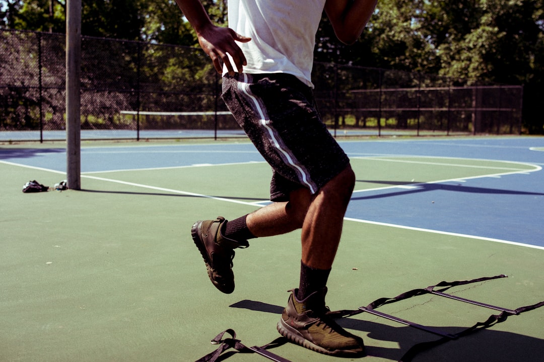man in white t-shirt and black shorts playing tennis