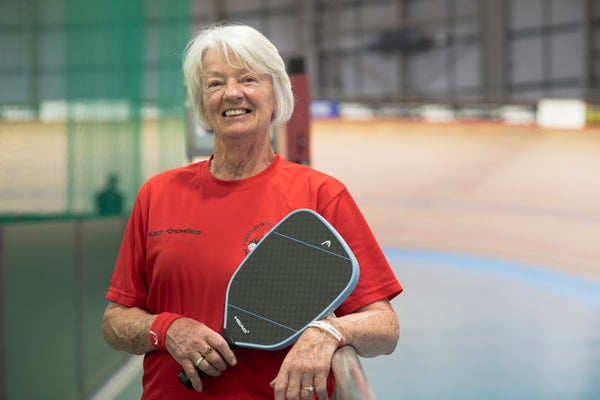 Smiling woman holding a pickleball paddle.
