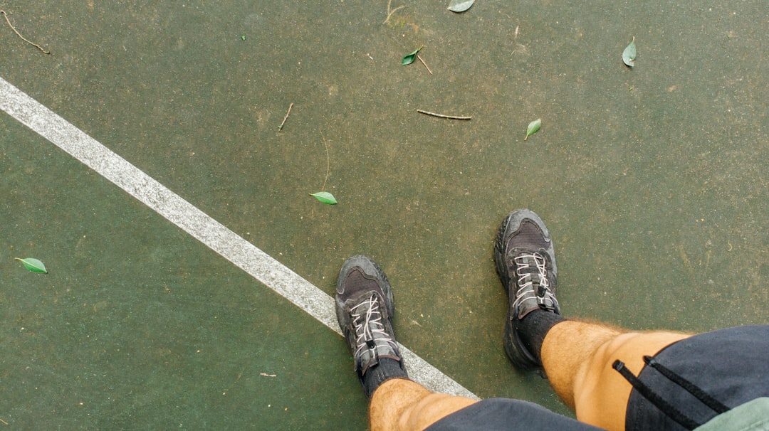 Feet standing on a green court with white line