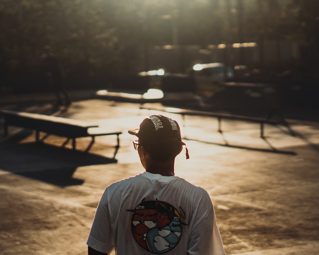 Person wearing a cap and t-shirt at a skatepark